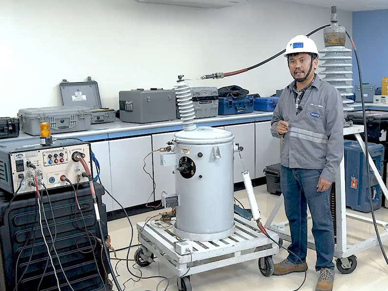 A man wearing a hard hat is standing in front of a machine.