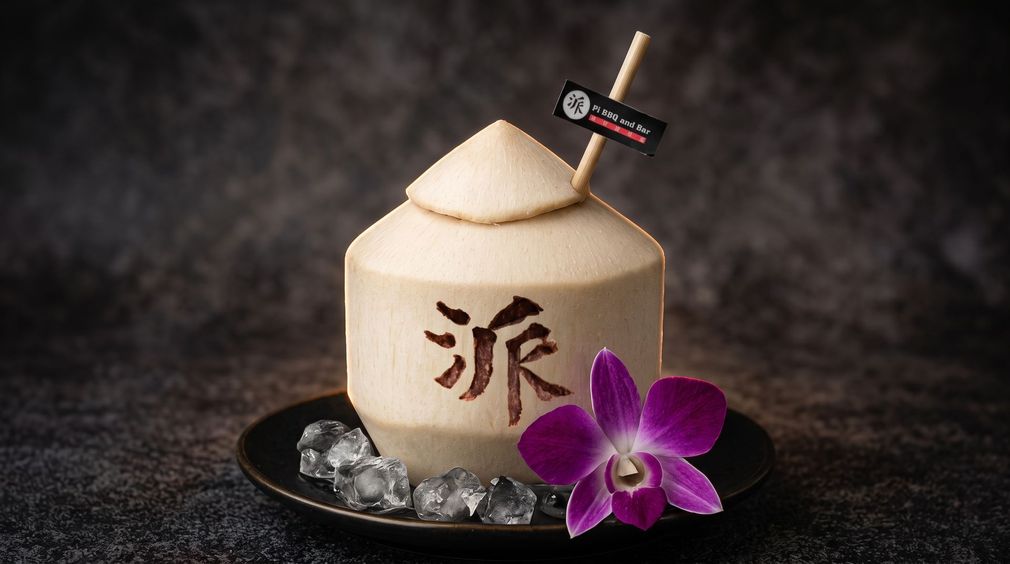 Bamboo cocktail in a coconut with ice, purple orchid, and a smoky dark background