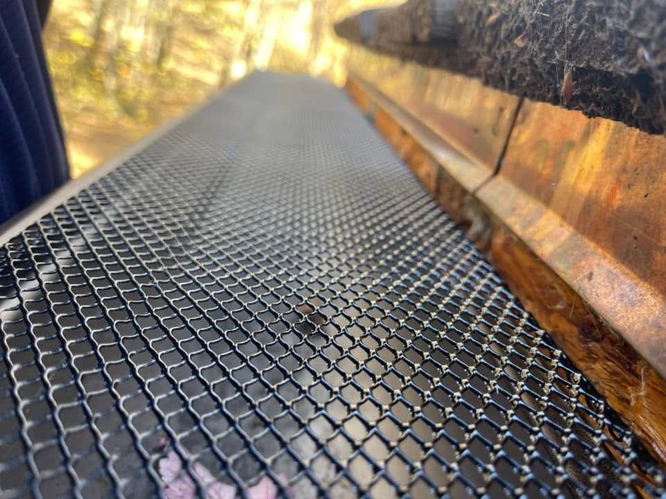 Black metal mesh walkway receding into the distance beside a wooden wall, with warm light in the background