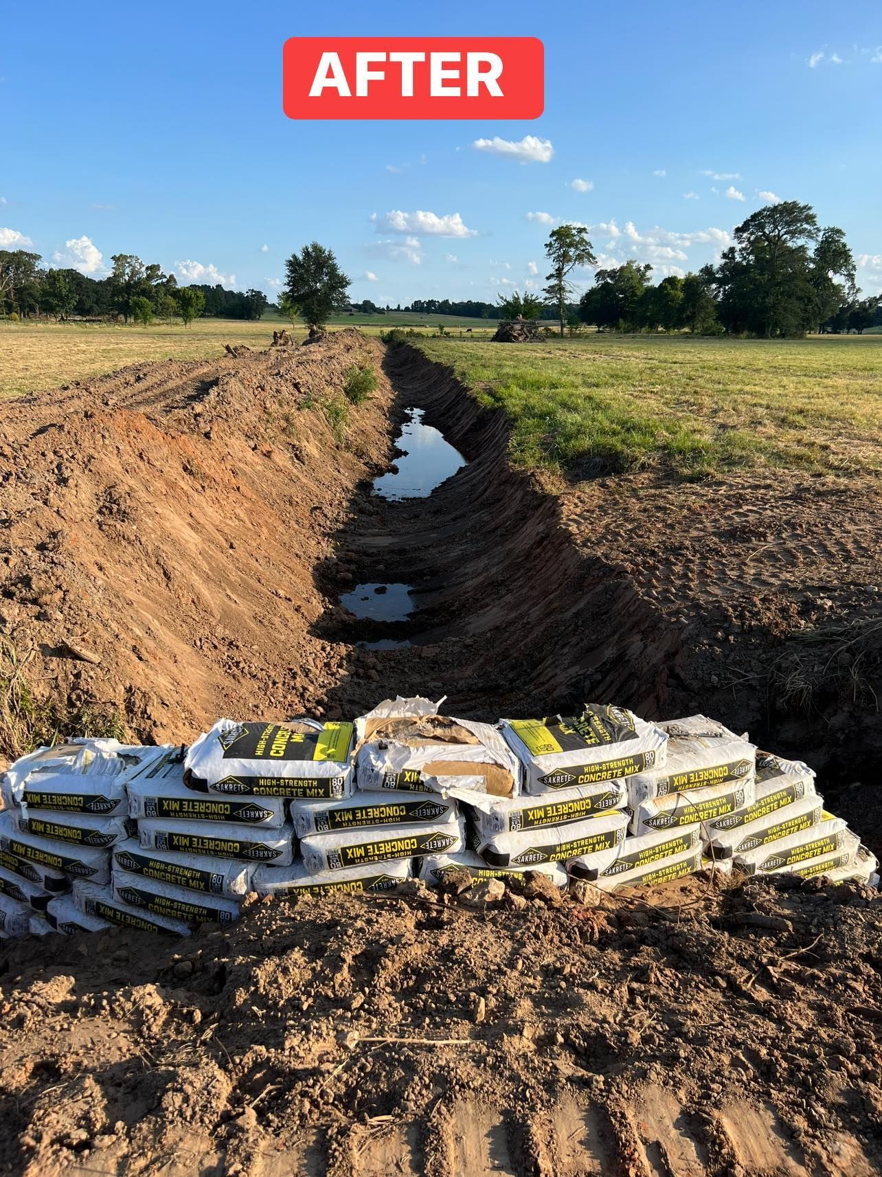A dug drainage ditch in a field, a wall of bags at the edge, labeled 