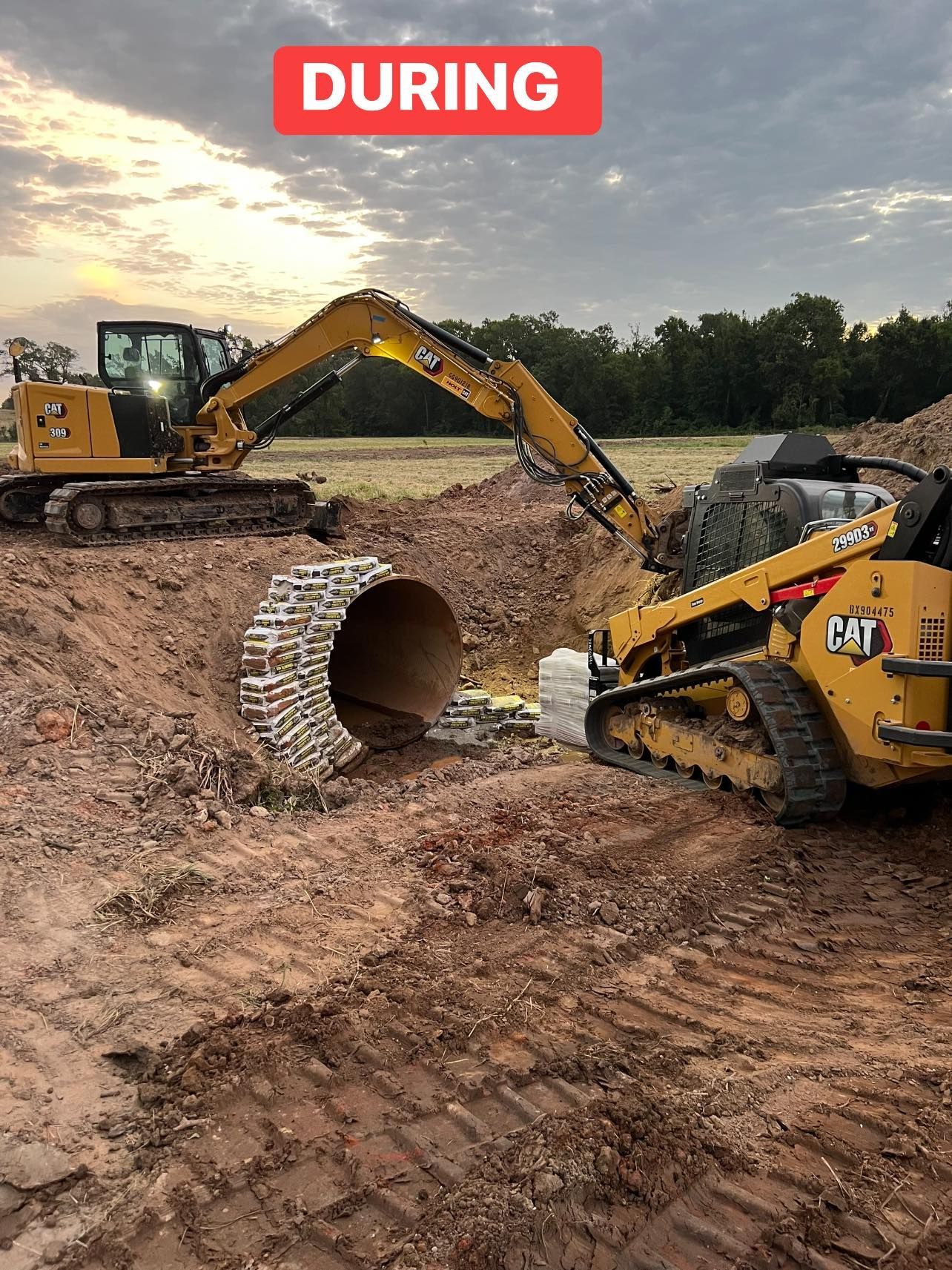Excavator and skid steer working on a construction site, moving dirt. Cloudy sky.