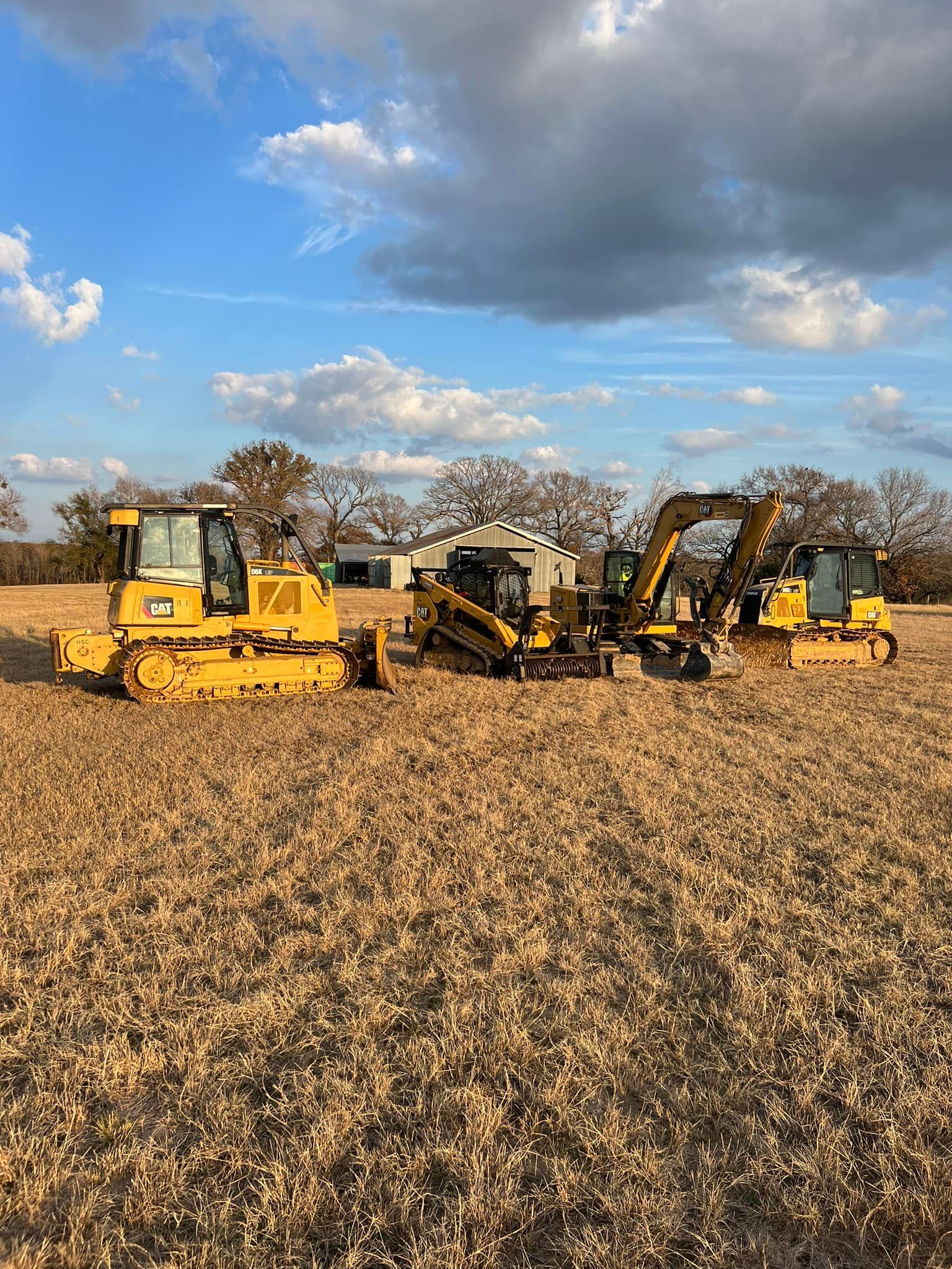 Yellow construction equipment in a field under a cloudy sky.
