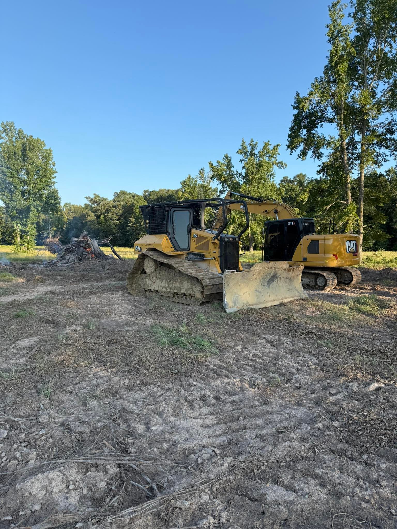 Yellow bulldozer clearing land under a blue sky.