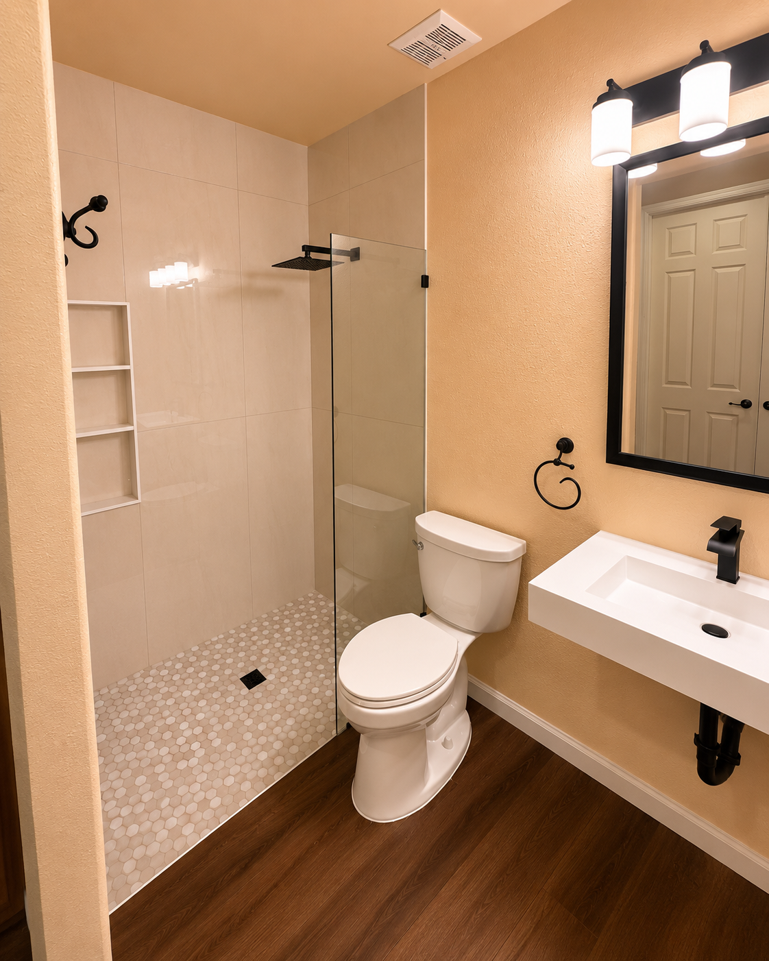 Small bathroom with walk-in shower, toilet, wall sink, mirror, and wood-look floor.