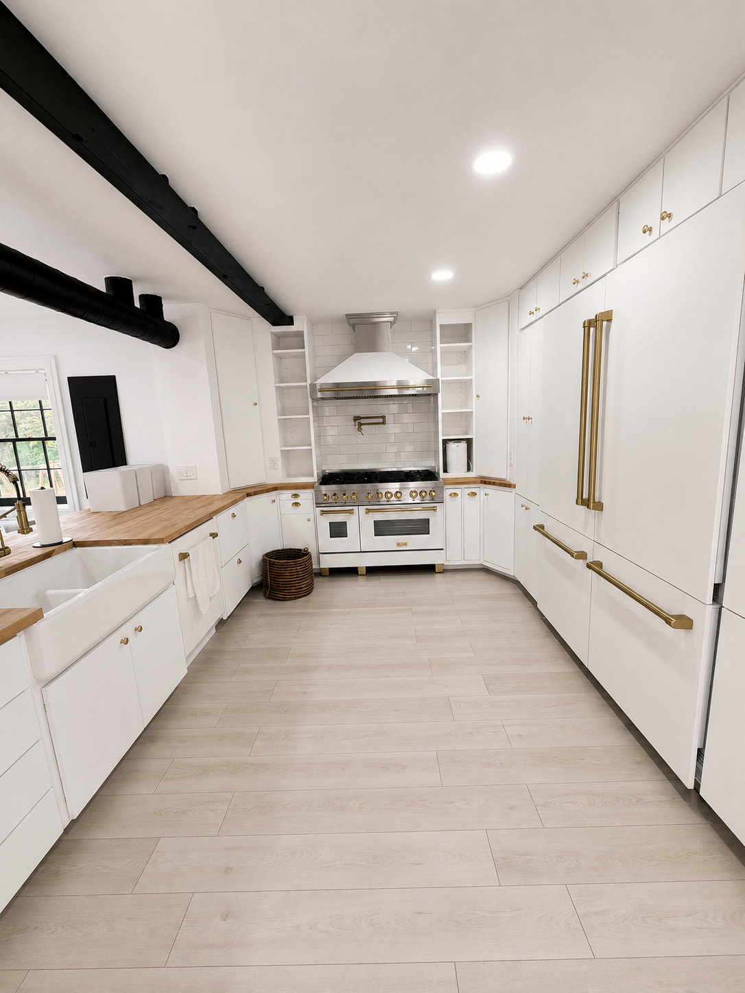 Bright white kitchen with long counters, gold handles, black beams, and a stove at the far end.