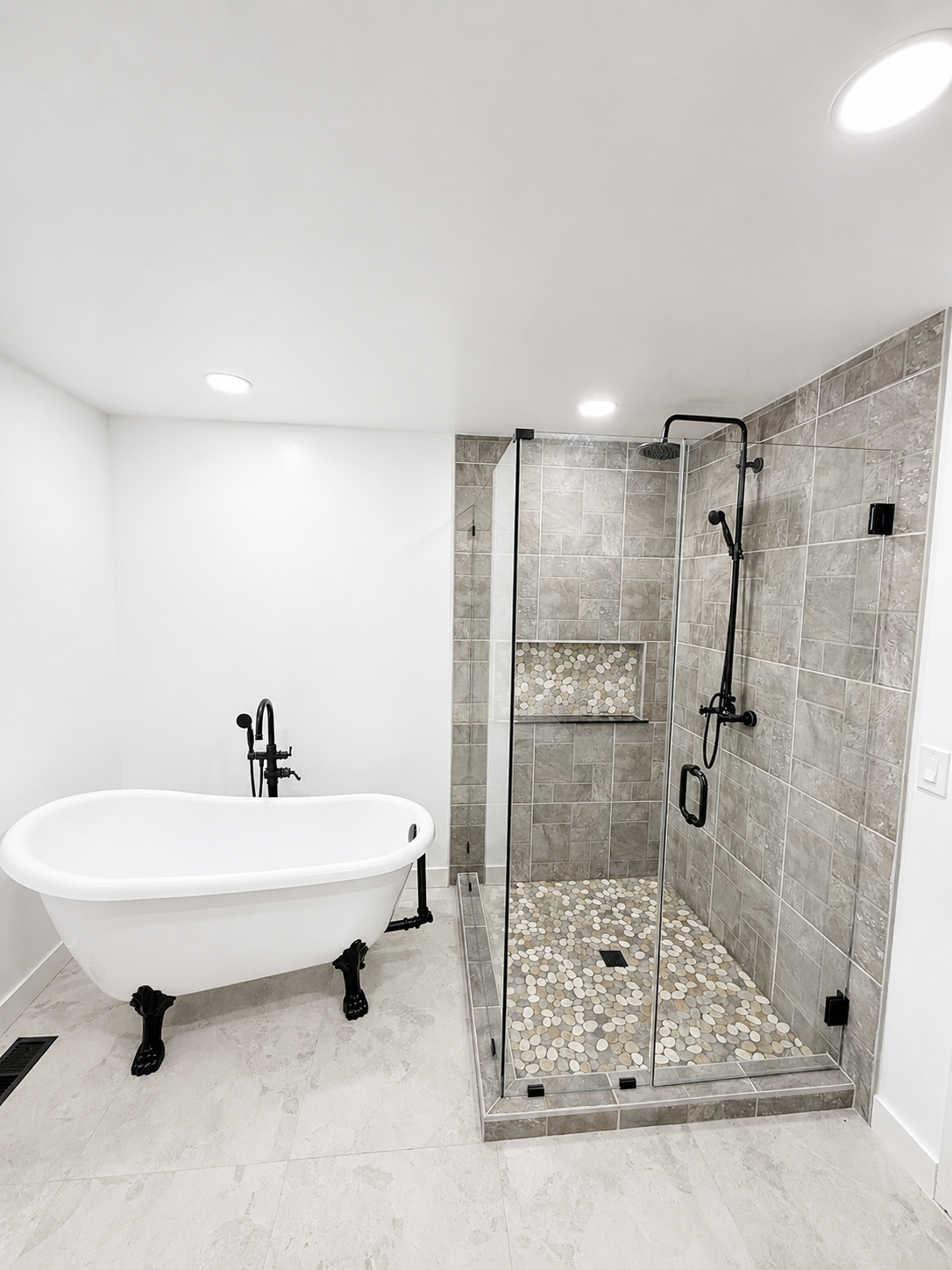 Bright bathroom with a freestanding tub and tiled glass shower stall under recessed lights