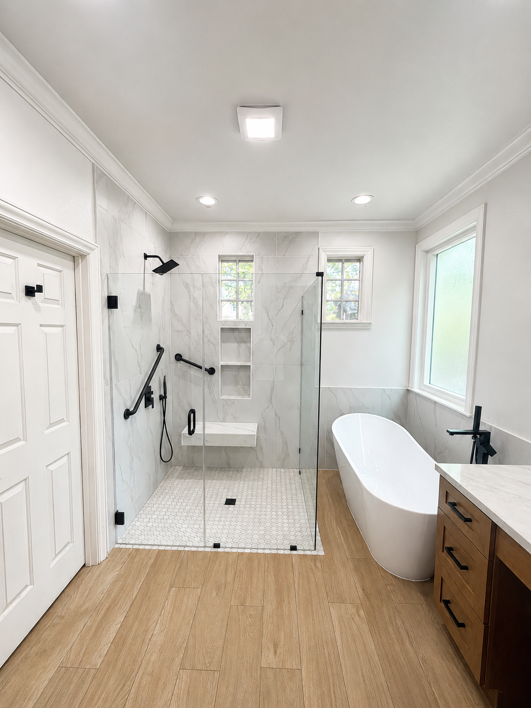 Bright white bathroom with walk-in shower, freestanding tub, and wood vanity in a modern interior.