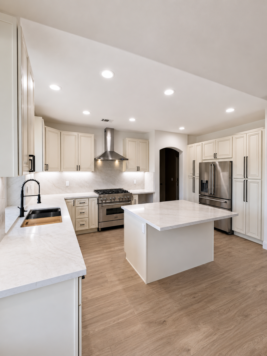 Bright modern white kitchen with stainless steel appliances, island, and recessed ceiling lights