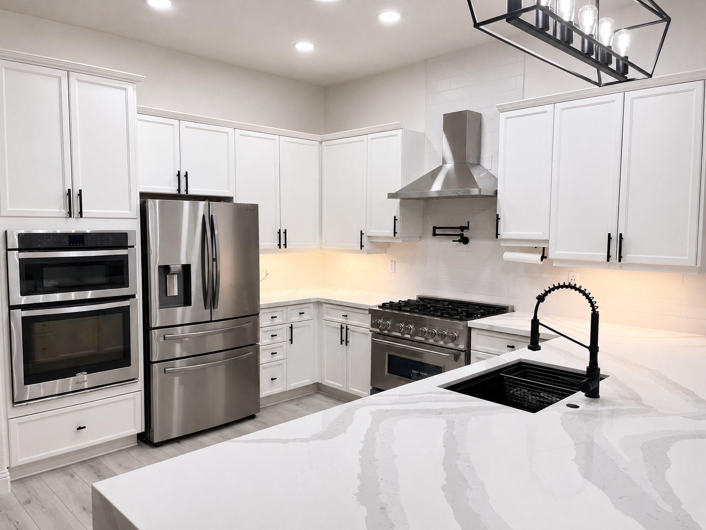 Bright modern white kitchen with stainless steel appliances, island, and black fixtures