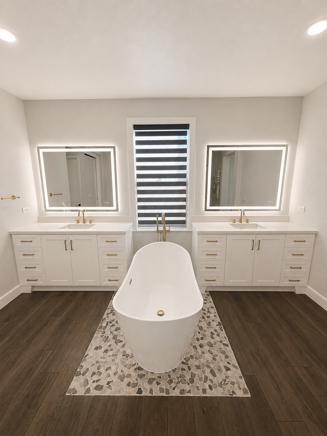 Bright bathroom with a freestanding tub, double vanities, and striped window shades.