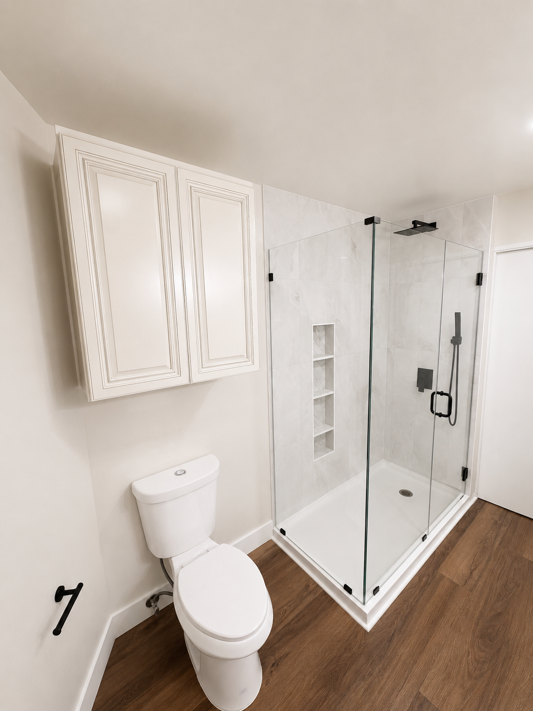 Small white bathroom with toilet, mirrored cabinet, and glass walk-in shower in a beige room