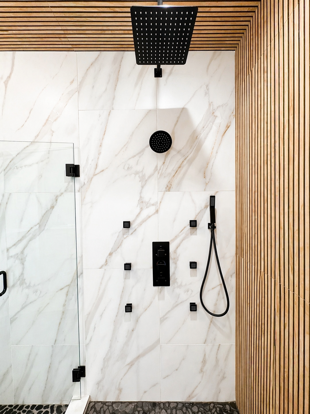 Modern shower with black fixtures, white marble wall, and wood slat accent panel