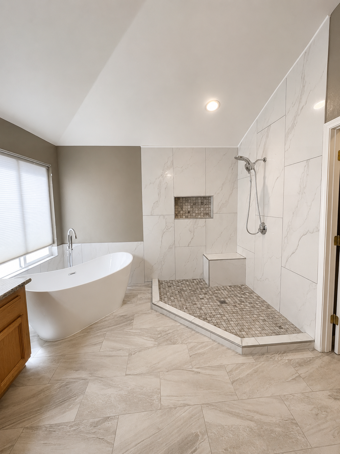 Bright modern bathroom with freestanding tub, glass shower, and marble tile walls and floor