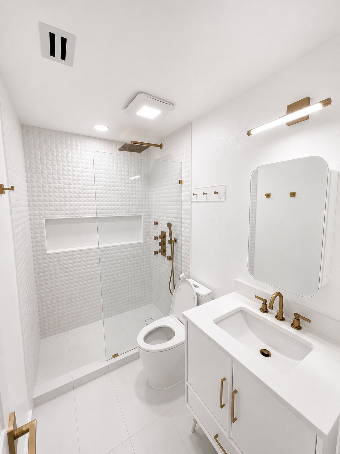 Bright white bathroom with glass shower, toilet, sink vanity, and mirrored cabinet