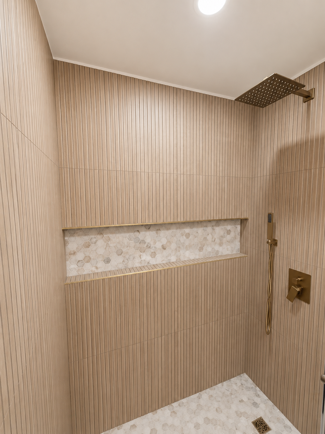 Small tiled shower with wood-pattern walls, built-in niche, and overhead rain showerhead.