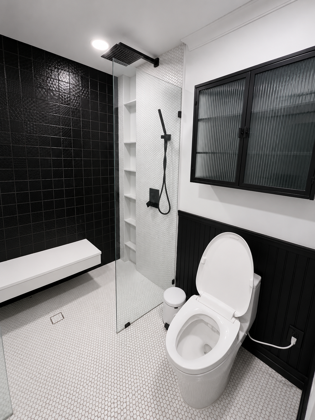 Modern black-and-white bathroom with shower, toilet, bench, and frosted window