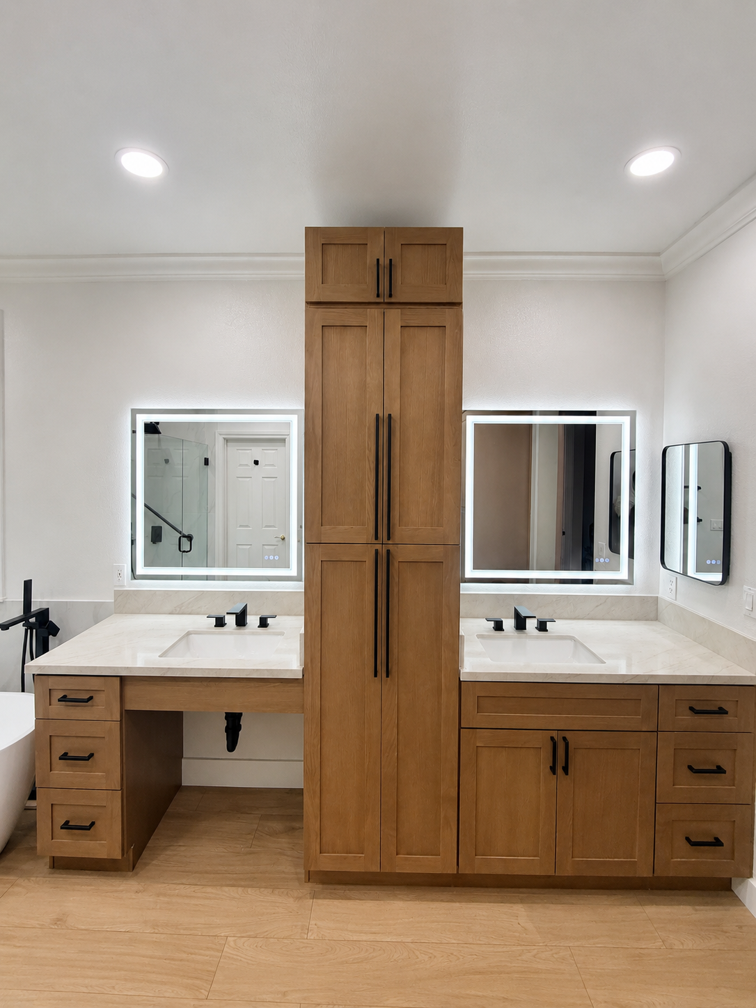 Double vanity bathroom with wood cabinets, white countertops, and mirrors on a bright white wall.