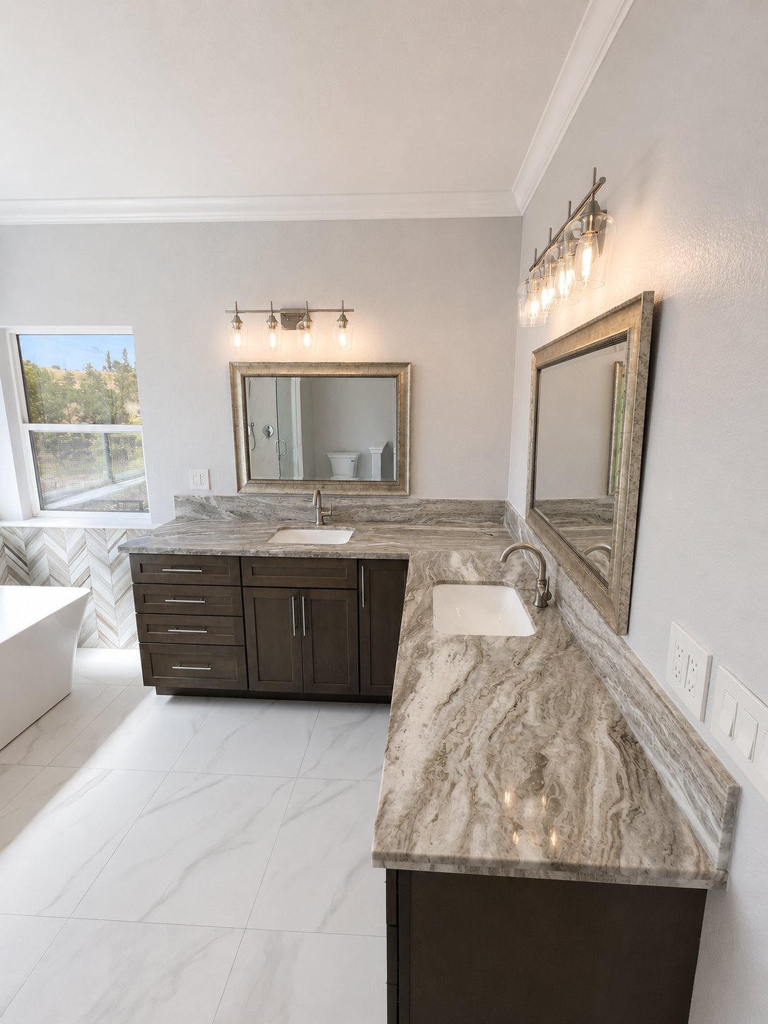 Bright bathroom with marble vanity counters, large mirror, wall sconces, tub, and white tile floor.