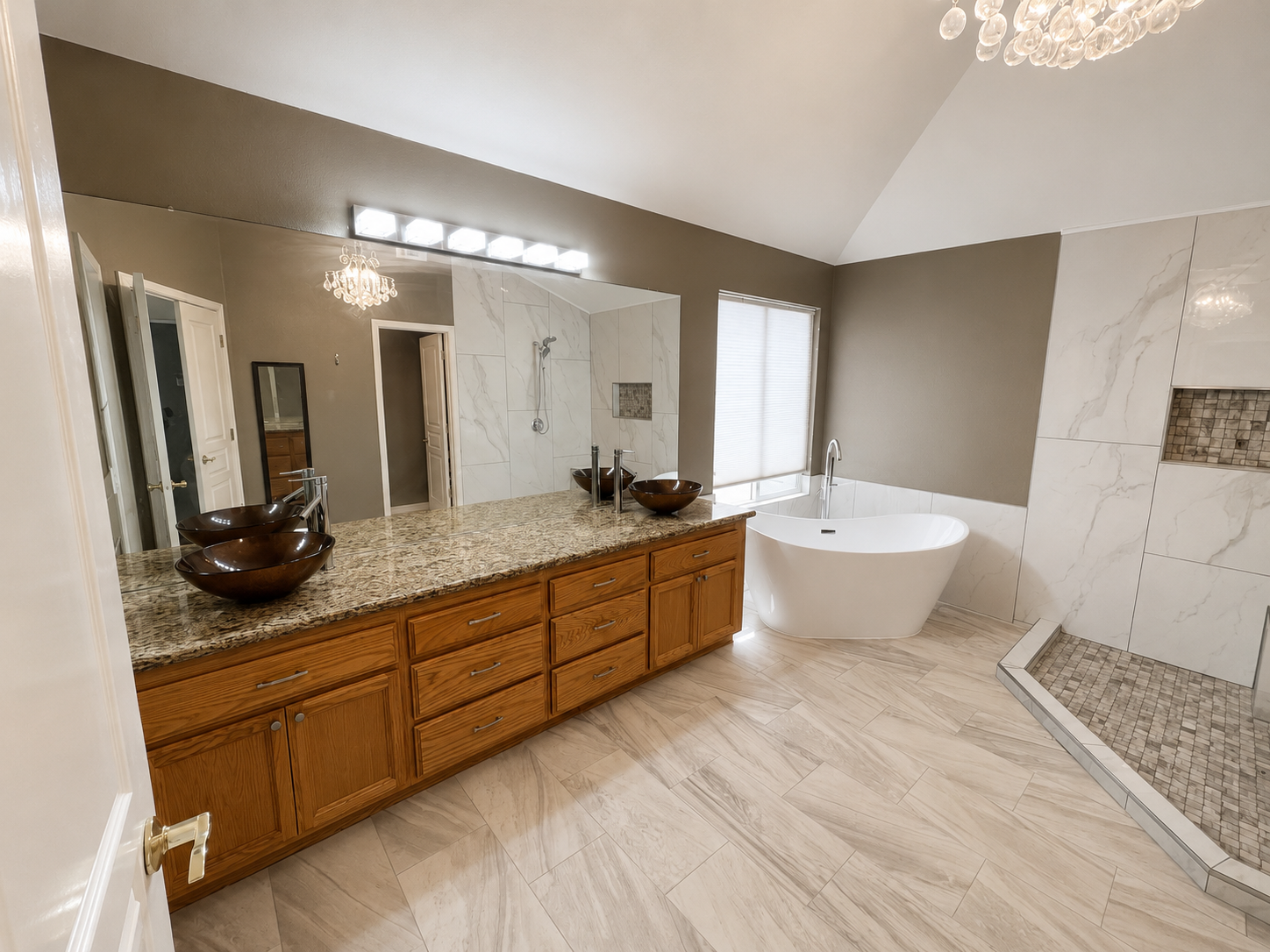 Spacious bathroom with double vanity, large mirror, freestanding tub, and tiled walk-in shower