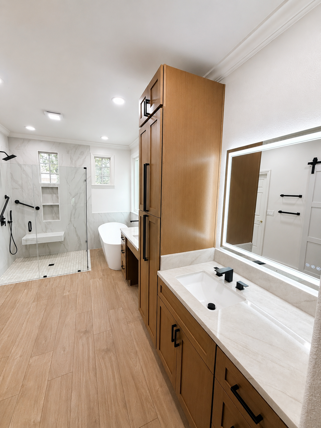 Bright modern bathroom with wood vanity, large mirror, and white tub-shower area