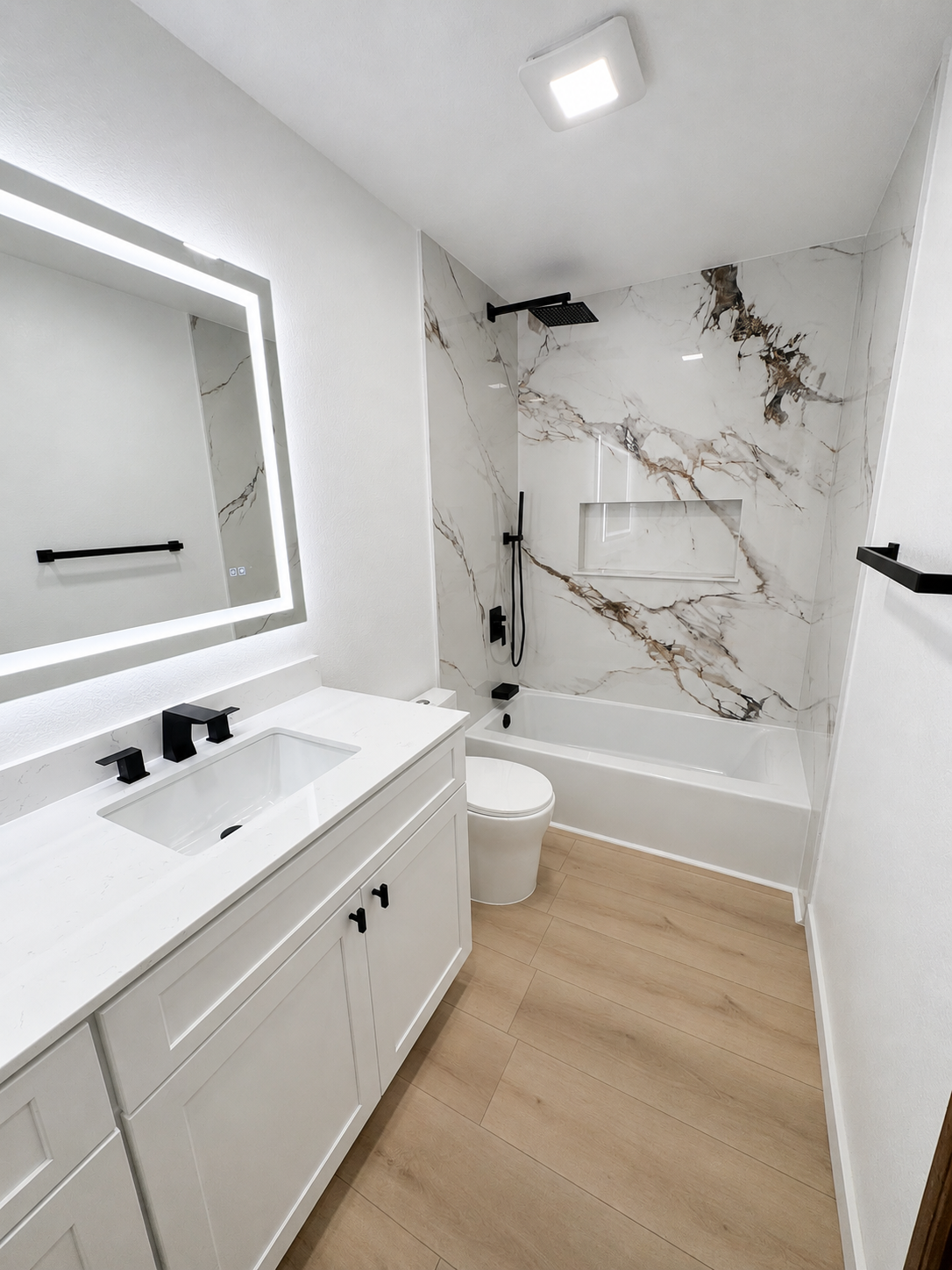Modern white bathroom with tub shower, vanity, mirror, and light wood flooring