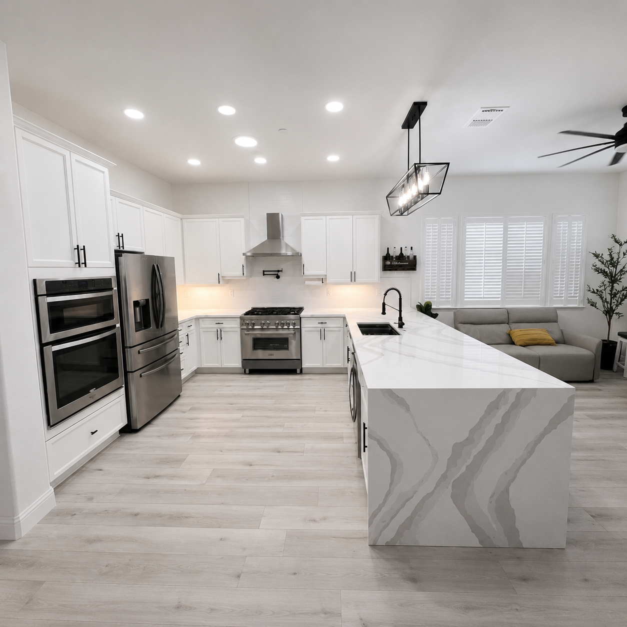 Bright modern kitchen with white cabinets, stainless appliances, marble island, and adjacent living area