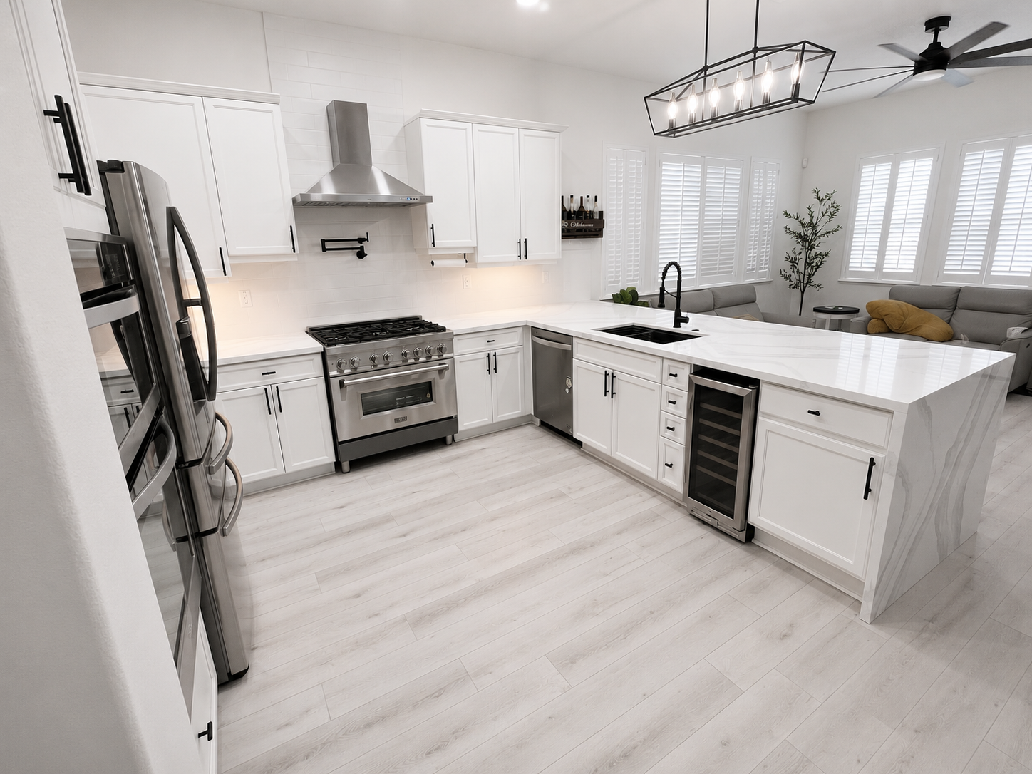 Bright modern white kitchen with island, stainless steel appliances, and light wood flooring