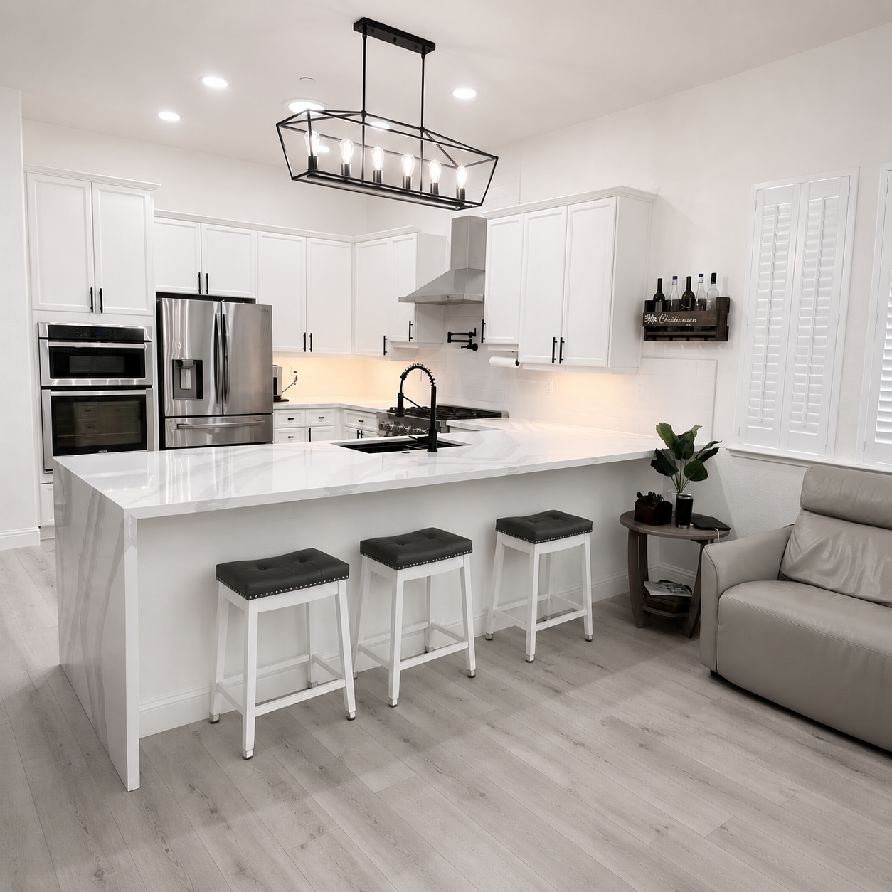 Bright white modern kitchen with island, three stools, stainless appliances, and beige sofa nearby.