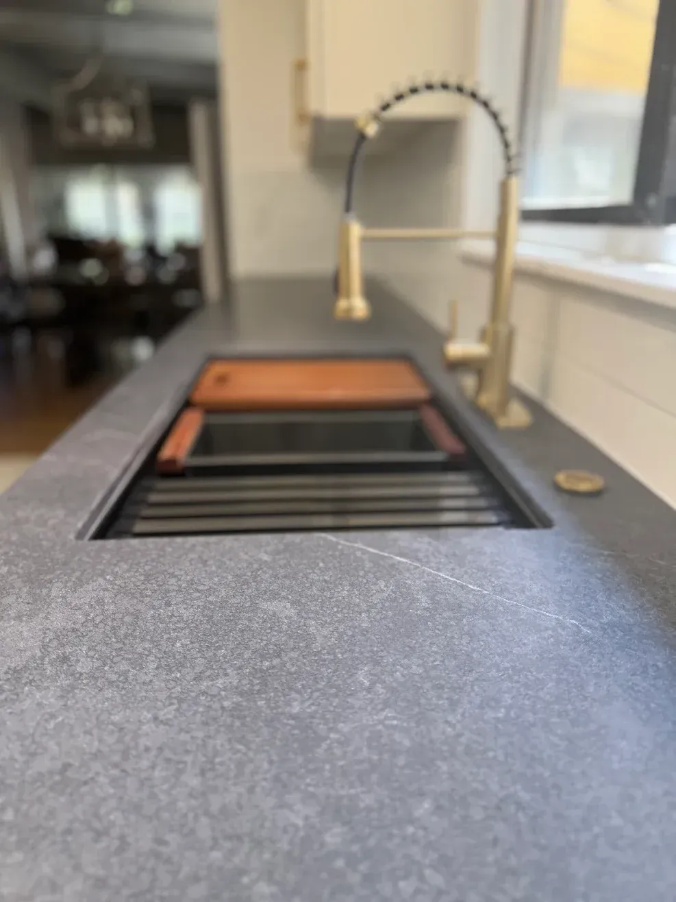 Modern kitchen sink with a high-arc faucet and window in the background