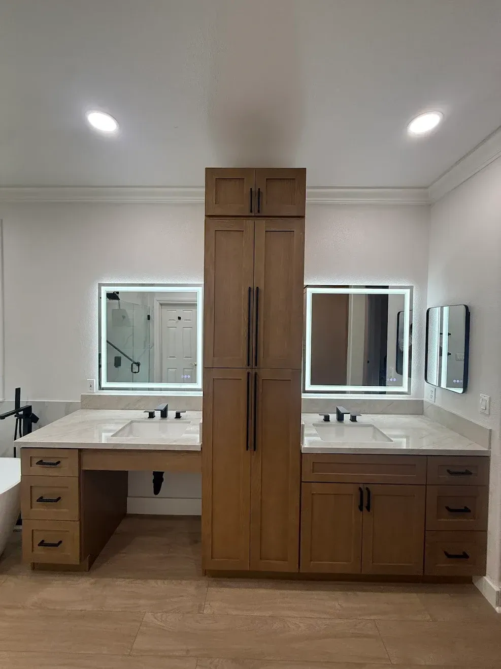 Modern double vanity bathroom with wood cabinetry, white countertops, and large mirrors.