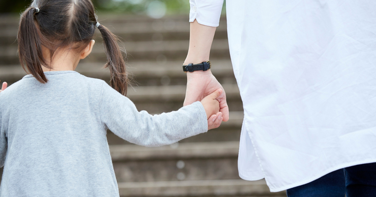 Adult holding a child's hand while walking up outdoor steps Adult holding a child's hand while walking up outdoor steps