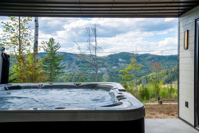 Hot tub on a covered patio overlooking a mountain landscape and cloudy sky