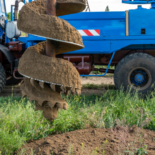 A blue truck is digging a hole in the ground