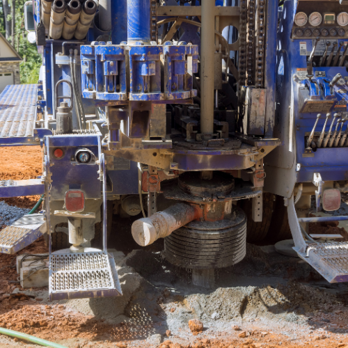 A large blue machine is sitting on top of a pile of dirt.