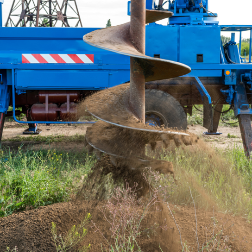 A blue truck is digging a hole in the ground.