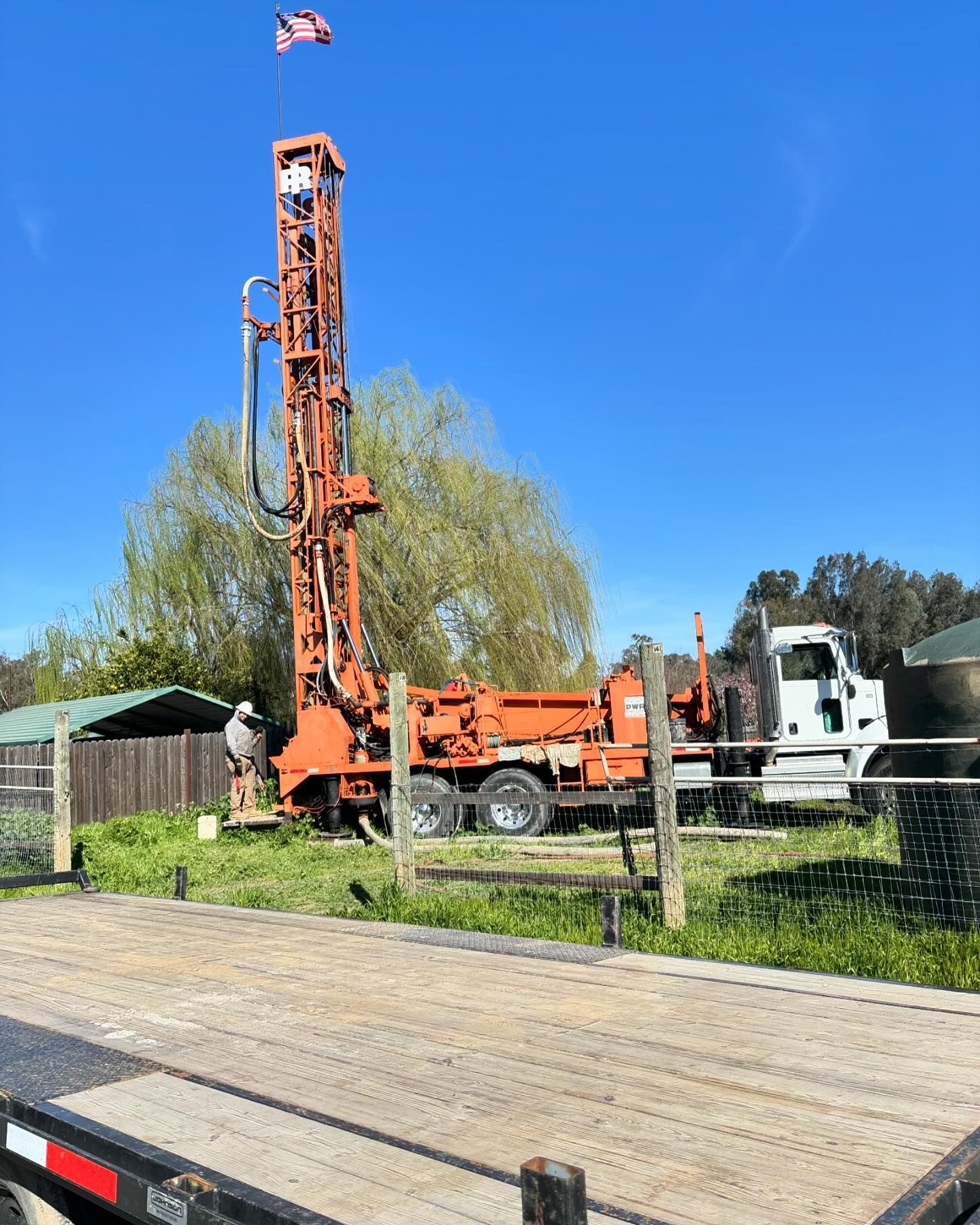 A drilling rig is sitting on top of a trailer in a field.