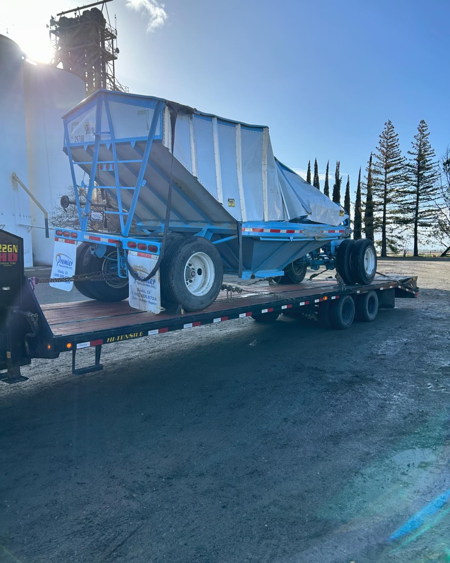 A blue trailer is sitting on top of a flatbed trailer.