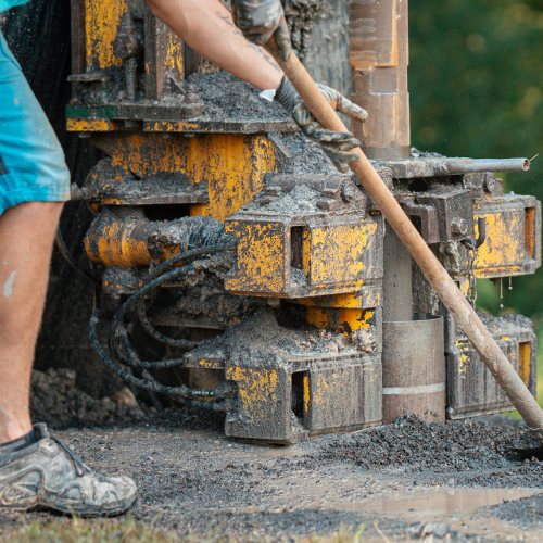 A man is working on a machine that is covered in mud.