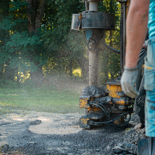 A man is using a machine to dig a hole in the ground.