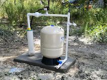 A water tank is sitting on top of a concrete platform in the dirt.