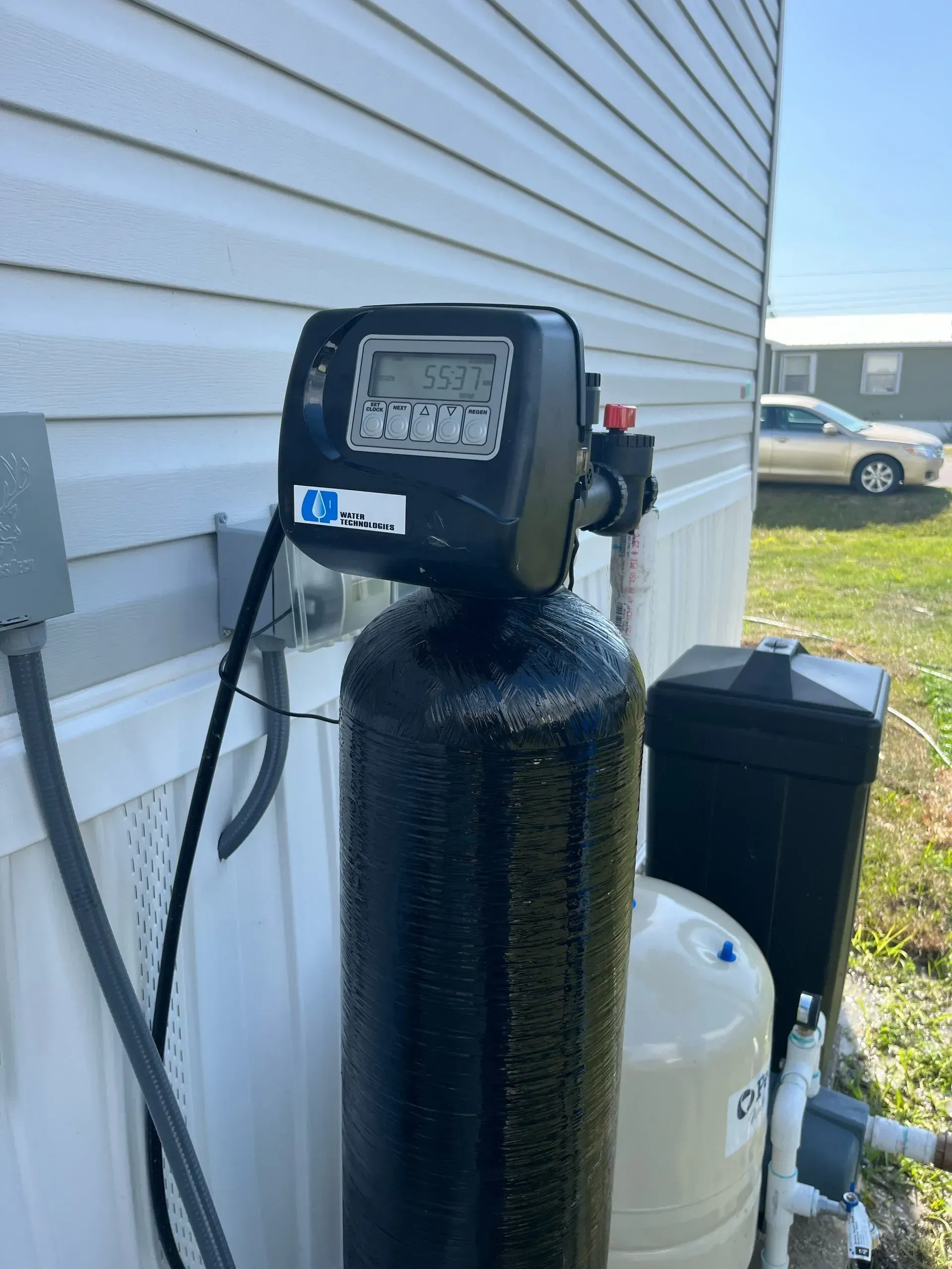 A water filter is attached to the side of a house.