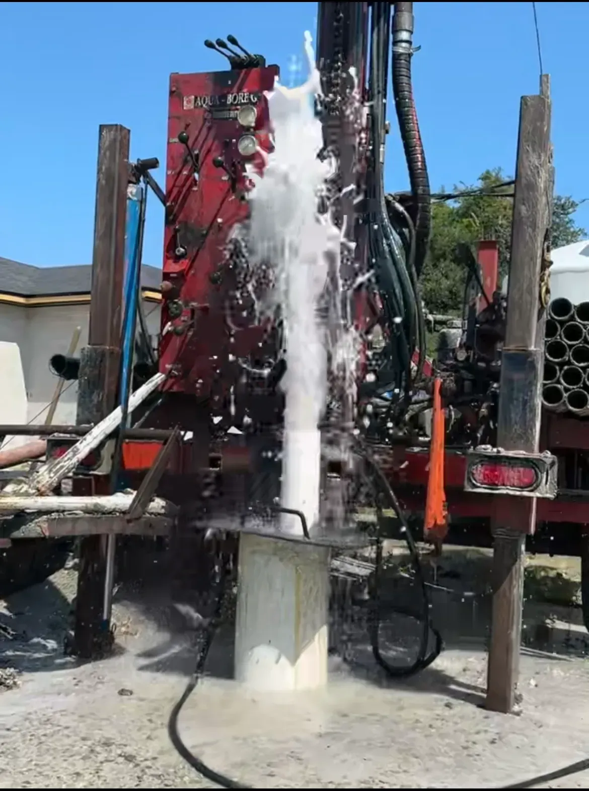 A drill is drilling a hole in the ground and water is coming out of it