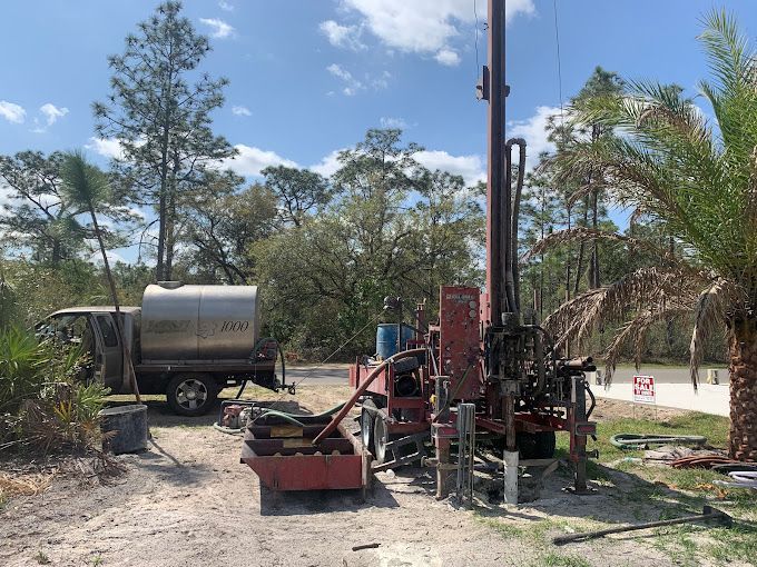 A large machine is sitting in the middle of a dirt field next to a truck.