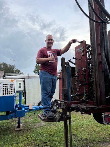 A man is standing on top of a machine in a field.