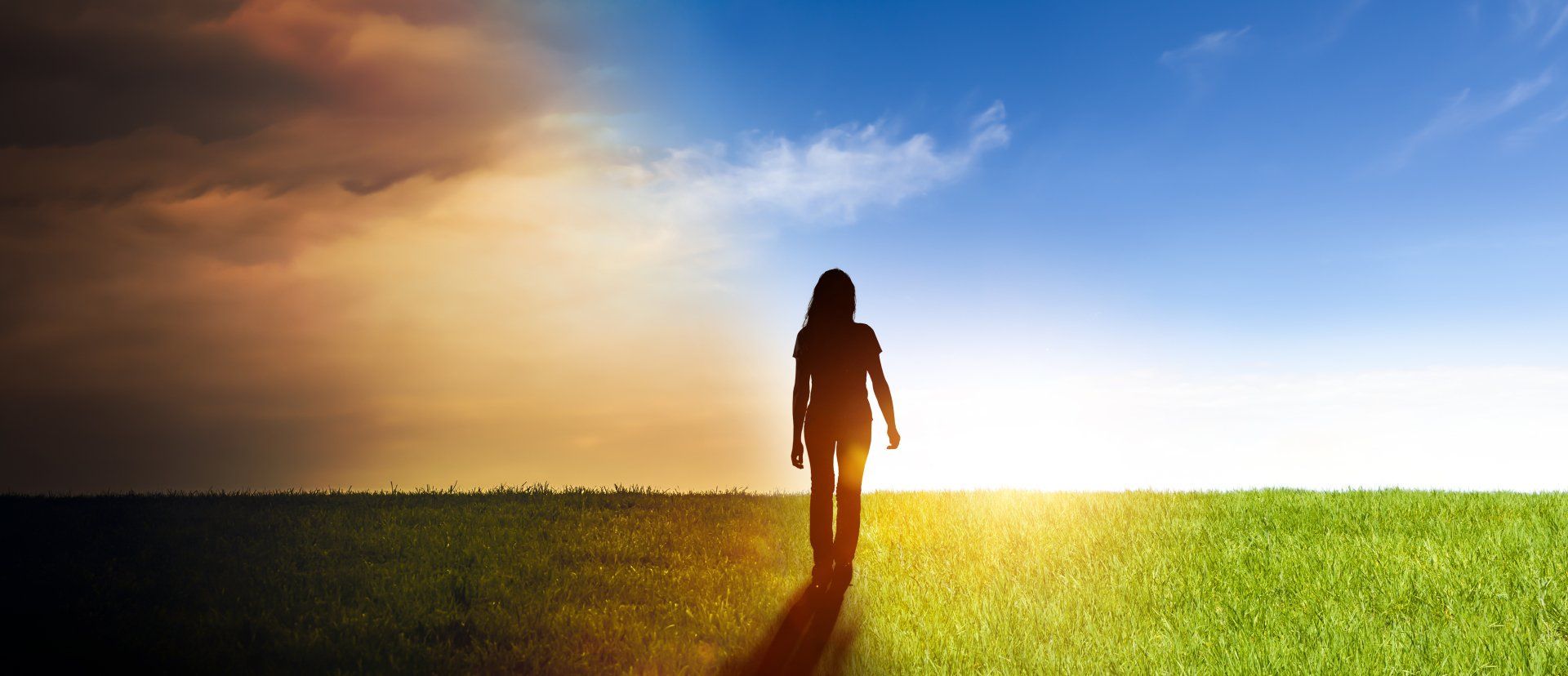 Femme marchant vers un ciel lumineux et ensoleillé depuis un ciel sombre et orageux, sur un champ herbeux.