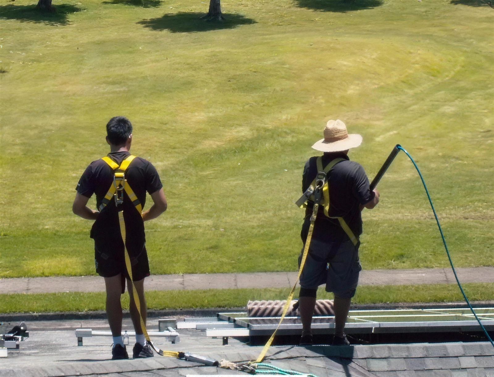 Two Sunshine techs in harnesses on a commercial roof