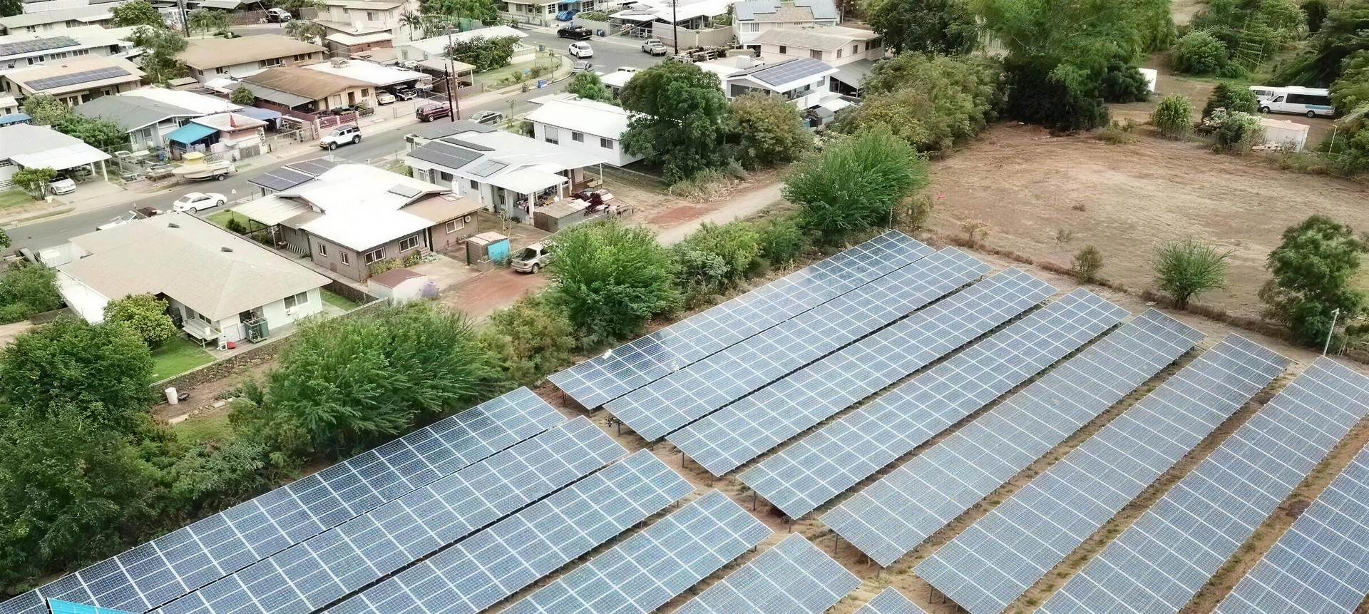 Drone view of a ground-mounted solar farm beside a neighbourhood on Oahu