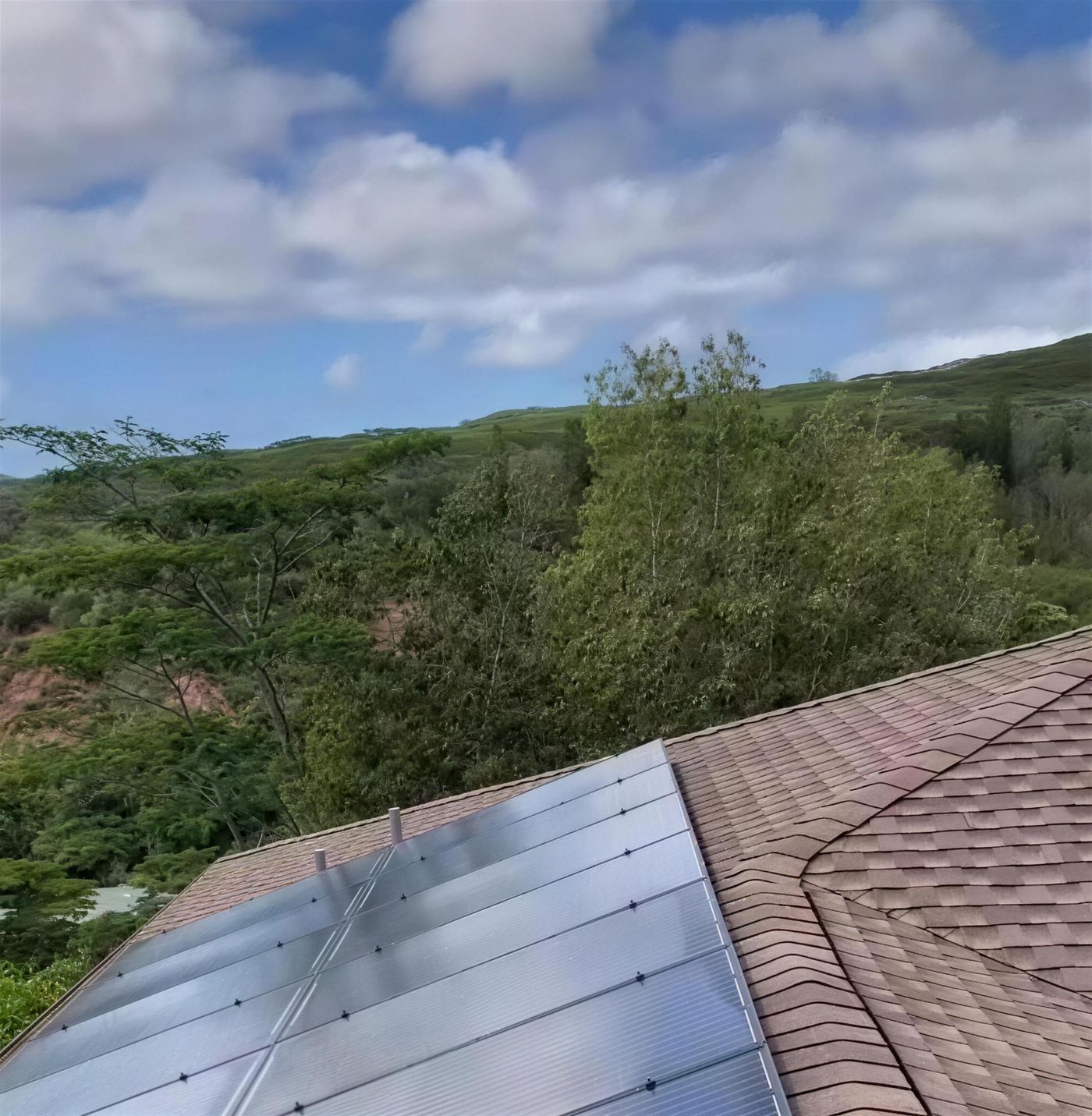 Solar panels on a Mililani roof, trees and the central ridge behind