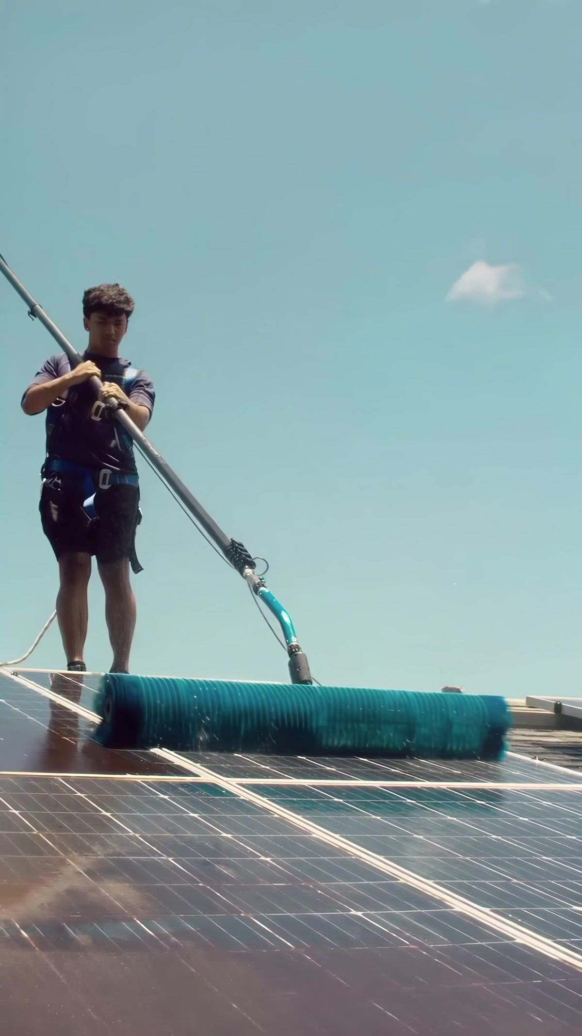 A Sunshine tech running the rotating brush across a residential solar array