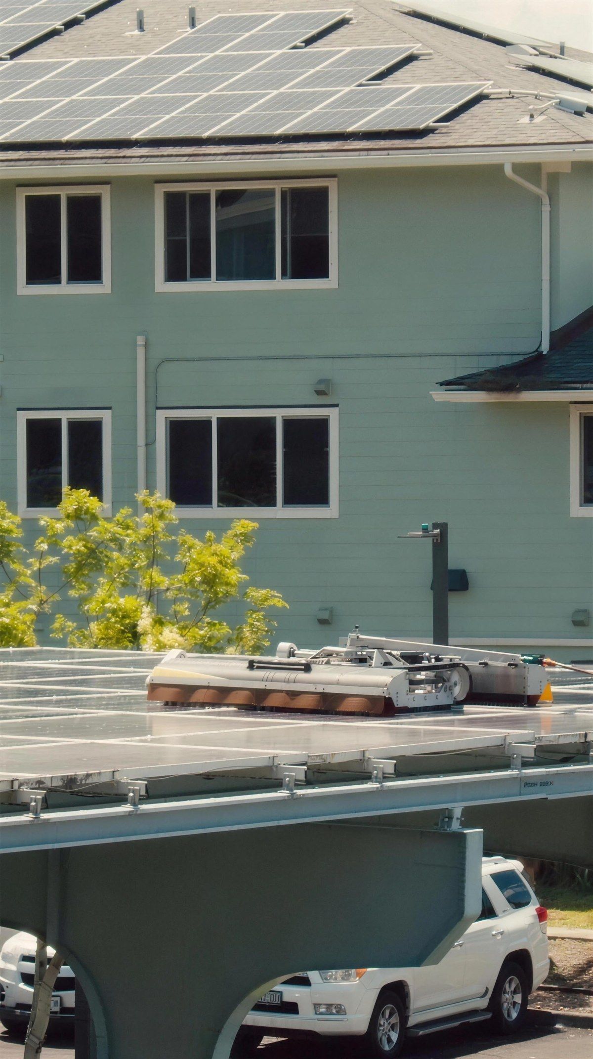 The cleaning robot on a parking-structure array beside a multi-storey building